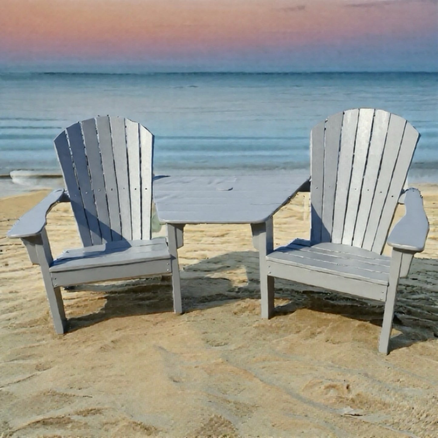Two gray Adirondack chairs with a small Tete table on a sandy beach.