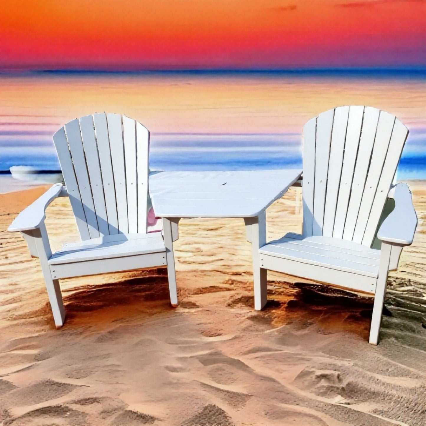 Two white  Adirondack chairs with a tete table on a sandy beach at sunset.