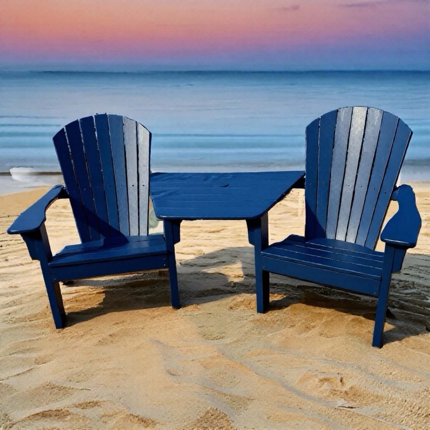 Two blue Adirondack chairs with a table on a sandy beach at sunset.